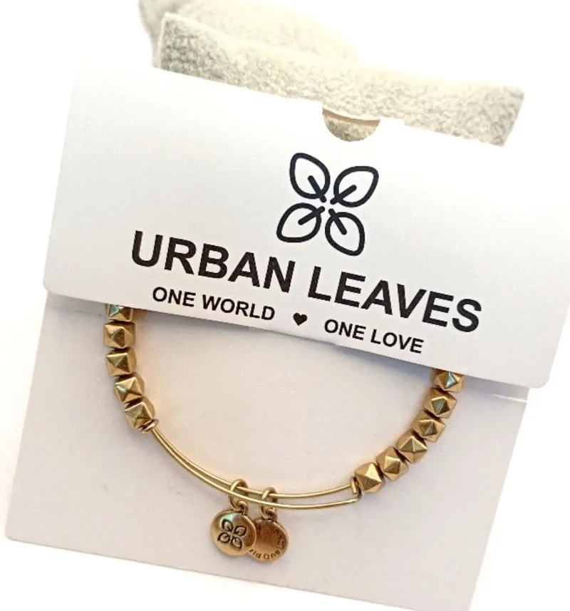 A gold-tone beaded bangle on its Urban Leaves card, printed One World, One Love