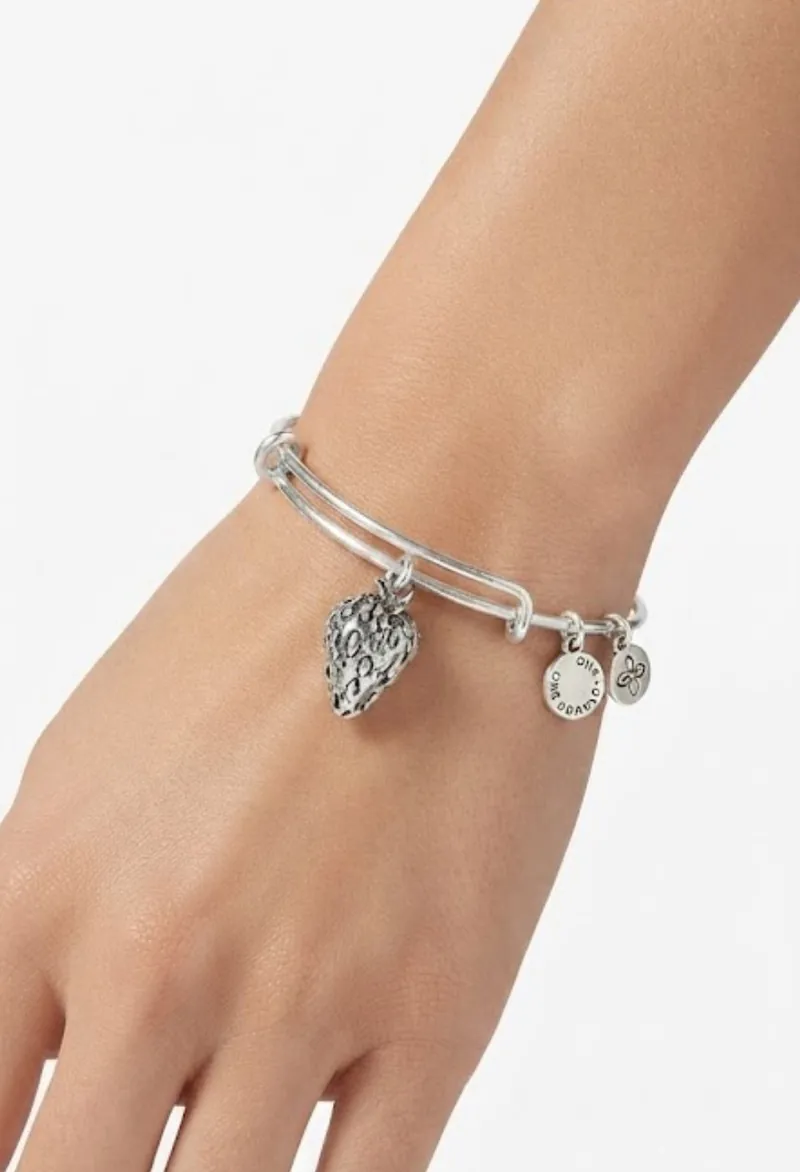 A silver-tone strawberry charm bangle worn on the wrist